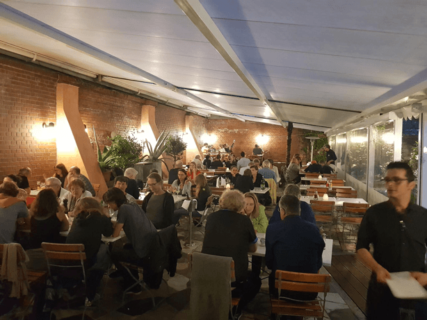 Il giardino d'inverno dell'Osteria N.1 con muri di mattoni, luci calde e tavoli pieni
