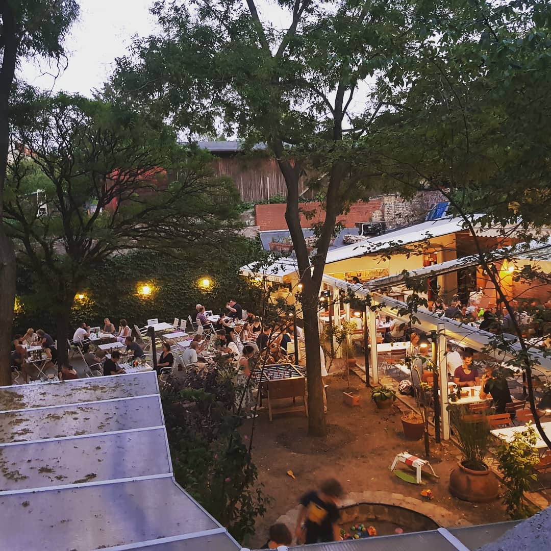 The courtyard of Osteria N.1 seen from above at dusk, with tables under the trees