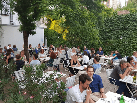 The summer garden of Osteria N.1 with white chairs and ivy-covered walls